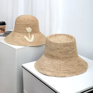 Two hand-woven raffia sun hats displayed on white cabinets for seaside holidays