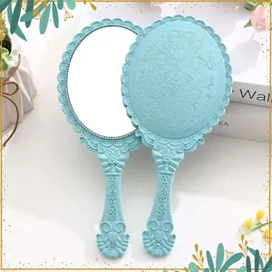 Detail of vintage blue handheld makeup mirror with intricate floral relief pattern