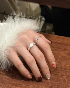 Detailed close-up of minimalist S925 sterling silver wavy brushed ring on a woman's hand