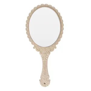 Vintage style handheld makeup mirror with an ornate beige carved frame detail design