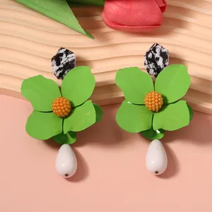 Close-up of vibrant green metal flower earrings with white teardrop-shaped pendants