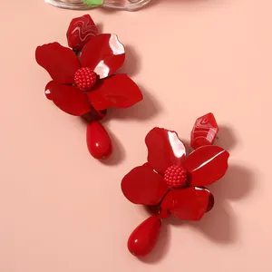 Macro shot of bold red metal flower earrings featuring elegant teardrop pendants.