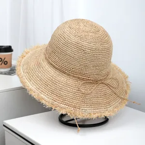High-quality natural raffia straw sun hat featuring a wide frayed brim and elegant bow