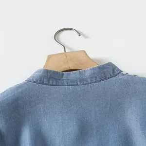 Close-up detail of a light blue tencel shirt with intricate white floral embroidery