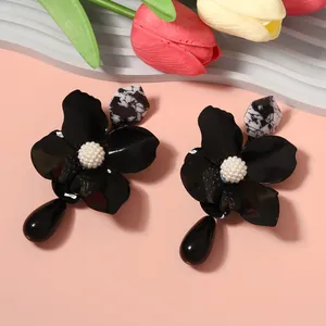 Close-up of black metal flower earrings with marble bead and waterdrop pendant