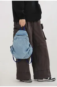 Modelo sosteniendo una mini mochila de mezclilla lavada azul claro en un entorno casual