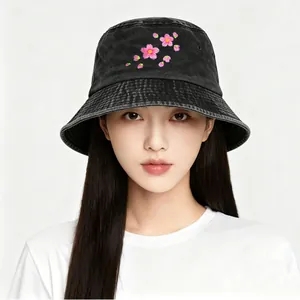 Close-up of pink cherry blossom embroidery on a washed black denim bucket hat.