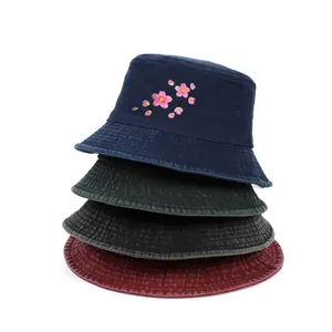 Detail view of stacked washed cotton bucket hats with delicate pink sakura embroidery.