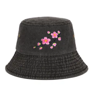 Detailed close-up of pink cherry blossom embroidery on a dark grey denim bucket hat