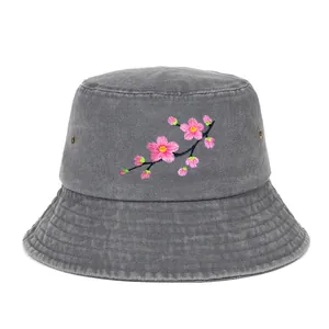 Detailed view of pink cherry blossom embroidery on a grey washed cotton bucket hat.