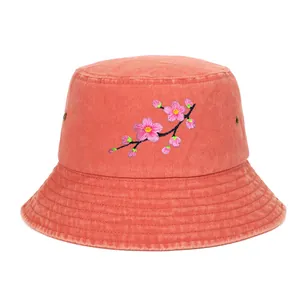 Detailed view of a coral bucket hat featuring delicate pink cherry blossom embroidery.