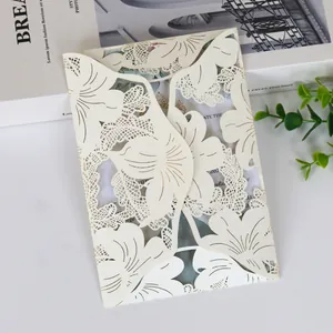 Close-up of elegant cream laser-cut floral invitation card with intricate hollow patterns