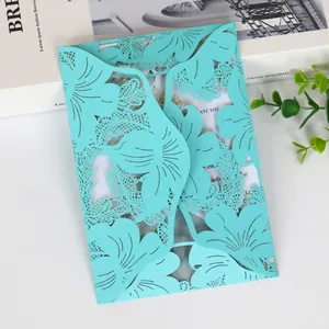 Detail view of teal laser-cut floral wedding invitation card with intricate leaf patterns