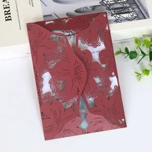 Intricate burgundy laser-cut leaf pattern on an elegant wedding invitation card