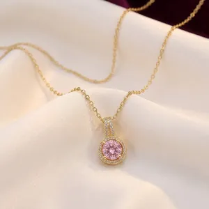 Elegant gold necklace with a round pink zircon pendant on white silk background