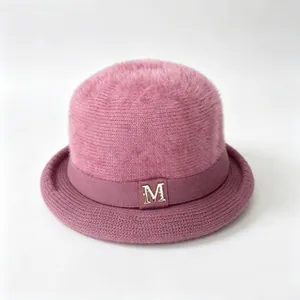 Detailed view of a pink fuzzy knit bucket hat featuring a gold M logo and a curled brim