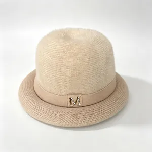 Elegant women's beige knitted bucket hat with faux fur top and rhinestone 'M' logo