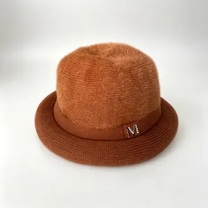 Detail of a rust-colored women's winter hat with fluffy fur top and knit rolled brim