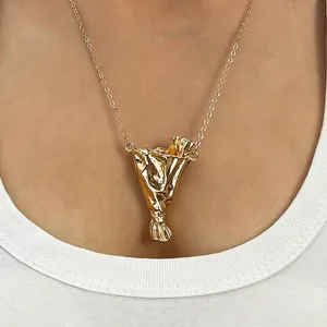 Dettaglio di una collana con ciondolo a borsa stropicciata dorata su una modella