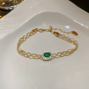 Elegant gold-tone beaded hollow bracelet with green gemstone centerpiece