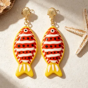 Vue détaillée de boucles d'oreilles poissons tropicaux avec clous coquillages dorés