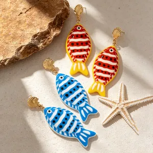 Vue détaillée de boucles d'oreilles poisson colorées avec clous en coquillage