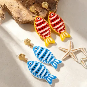 Vue détaillée de boucles d'oreilles poissons tropicaux colorés sur du sable