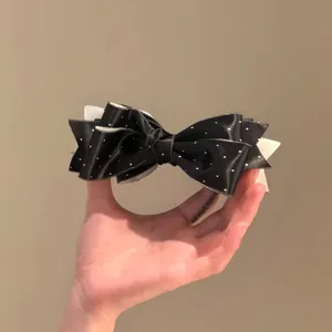Pince à cheveux élégante en tissu noir avec nœud à pois blancs pour un look raffiné