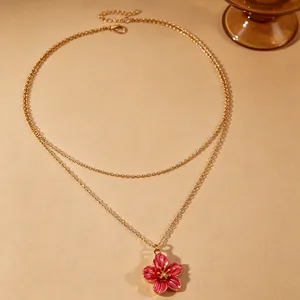 Detailed macro view of the delicate pink enamel flower pendant on a double gold chain