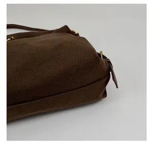 Detailed macro view of the thickened base on a brown canvas crossbody shoulder bag.