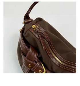 Close-up detail of a gold zipper on a brown canvas shoulder bag.