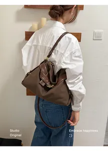 Back view of a woman wearing a stylish brown canvas shoulder bag with leather trim detail