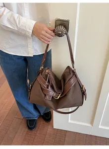 Casual brown canvas crossbody bag with adjustable leather strap and golden buckle detail