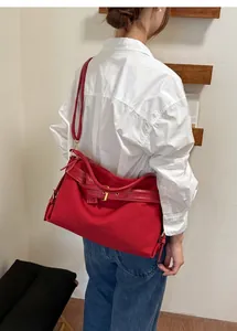 Casual red shoulder bag worn by a female model in a minimalist indoor studio setting