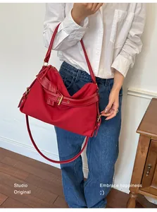 Stylish red canvas shoulder bag with belt buckle detail carried by woman in casual outfit