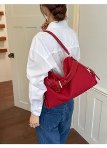 Vibrant red canvas crossbody bag with leather strap detail worn by a fashion model
