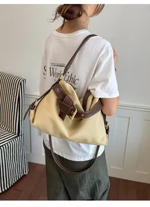 Detailed view of a canvas crossbody bag with decorative buckle on a model's shoulder