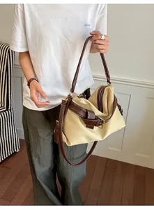 Lifestyle detail of a casual beige canvas crossbody bag with brown leather trim carried by a model
