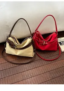 Detailed view of two minimalist hobo shoulder bags in beige and vibrant red color