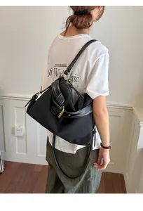 Side view of a stylish black canvas crossbody bag with knotted strap detail