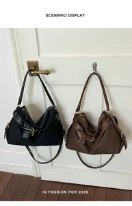 Pair of minimalist black and brown canvas shoulder bags hanging on a white door as a display