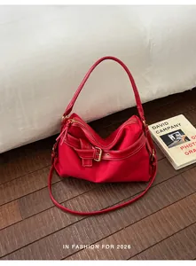 Red canvas and leather shoulder bag with buckle detail in a lifestyle setting