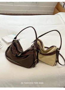 Two stylish canvas and leather shoulder bags in brown and beige shown on a white bed