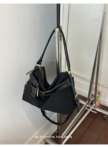 Detailed shot of a black canvas shoulder bag with leather trim hanging on a metal clothing rack