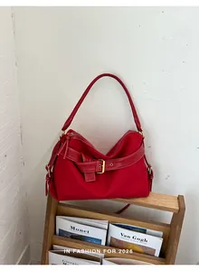 Stylish red minimalist shoulder bag for women displayed on a modern wooden rack