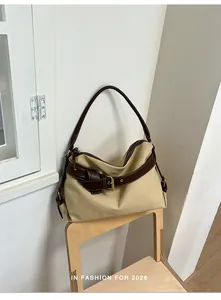 Minimalist canvas hobo bag with dark brown leather trim resting on a stylish wooden chair