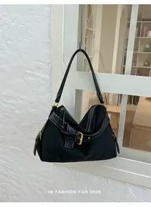 Close-up detail of a stylish black canvas shoulder bag featuring a decorative gold buckle