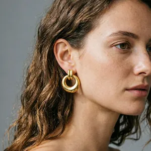 Close-up of exaggerated chunky gold-plated stainless steel earrings on model's ear