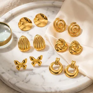 Macro view of six gold-plated stainless steel earring pairs featuring diverse artistic designs