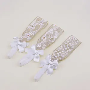 Close-up of white baby lace headbands featuring delicate floral embroidery and satin bows